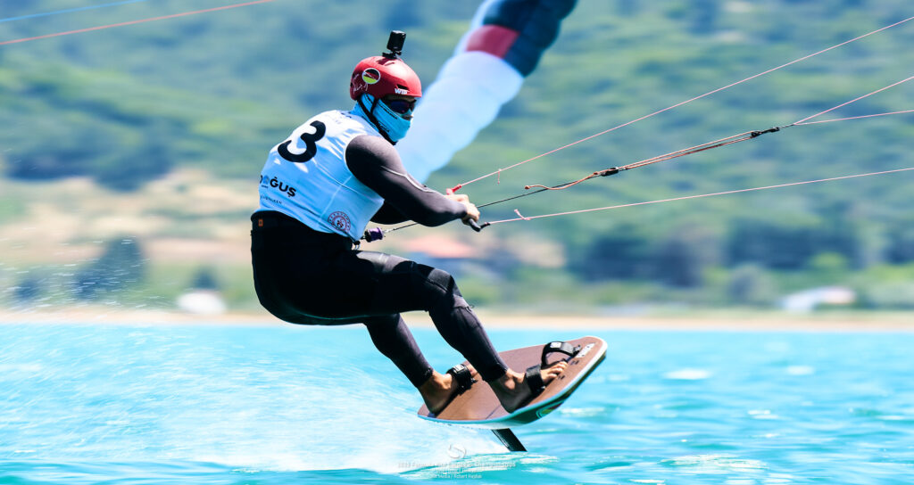 Jan Vöster aus dem German Sailing Team auf seinem Formula Kite-Board. Er schützt sein Gesicht mit einem Tuch gegen die Sonne. Auf dem Helm trägt er eine Kamera.