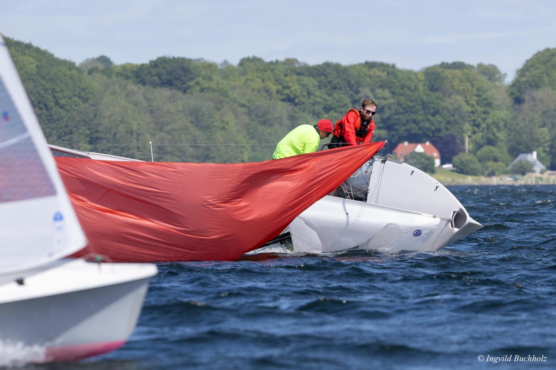 Eine 505er-Jolel ist gekentert und liegt auf der Seite. Der rote Spinnaker flattert. Die Crew versucht den 505er aufzurichten