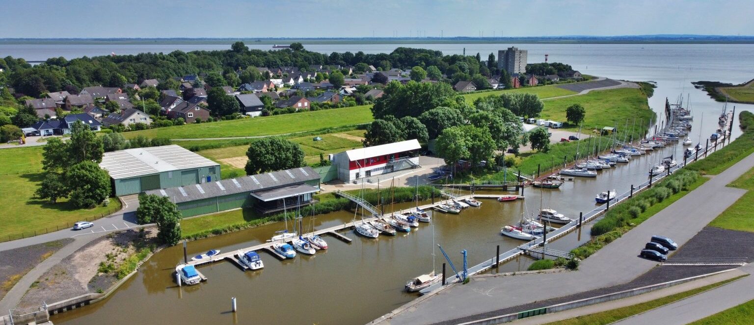 Das Foto zeigt den Hafen, die Stege mit Segelbooten und die Hallen der Seglervereinigung Brunsbüttel von oben.