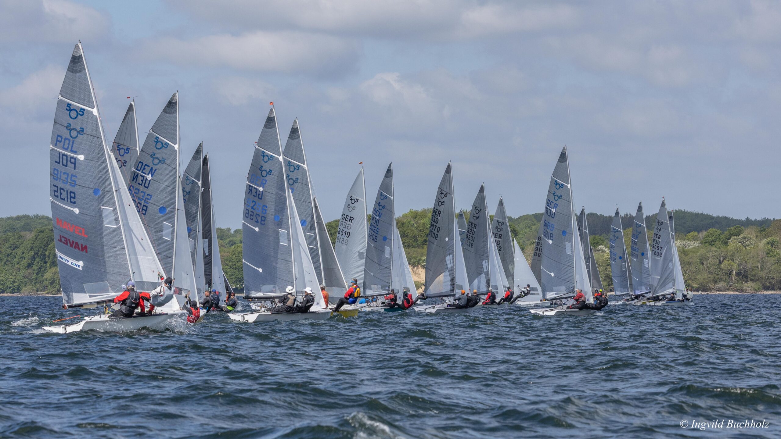 Viele 505er-Jollen segeln eine Wettfahrt auf der Flensburger Förde. Es ist windig, die Vorschoter stehen im Trapez