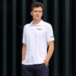 Ein dunkelhaariger Mann mit weißem Poloshirt guckt in die Kamera