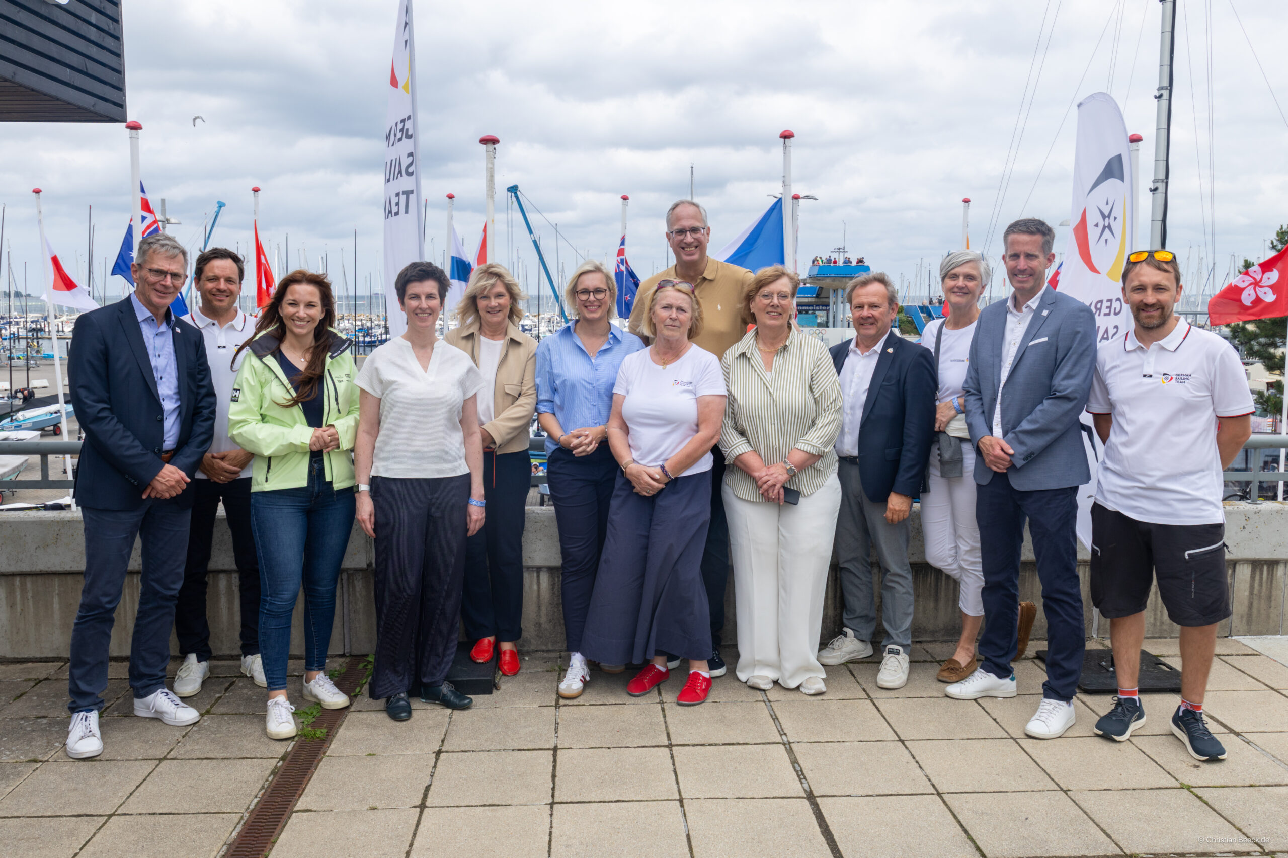 Gruppenfoto auf der Außenterrasse des Deutschen Segler Verbandes in Kiel-Schilksee mit Flaggen im Hintergund