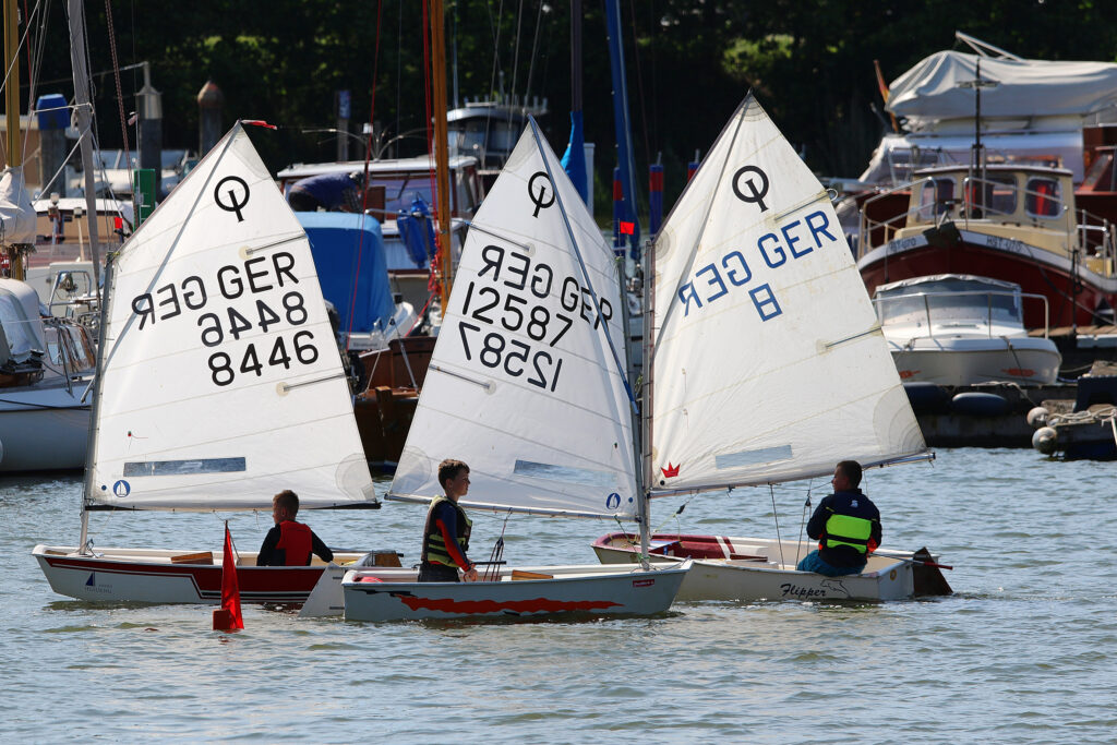 Drei Kinder segeln im Optimisten im Strelasund vor Stralsund