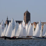 Viele Segelboote vom Typ Marinekutter starten zur Wettfahrt Rund Hiddensee. Im Hintergrund ist der Stralsunder Dom zu sehen.