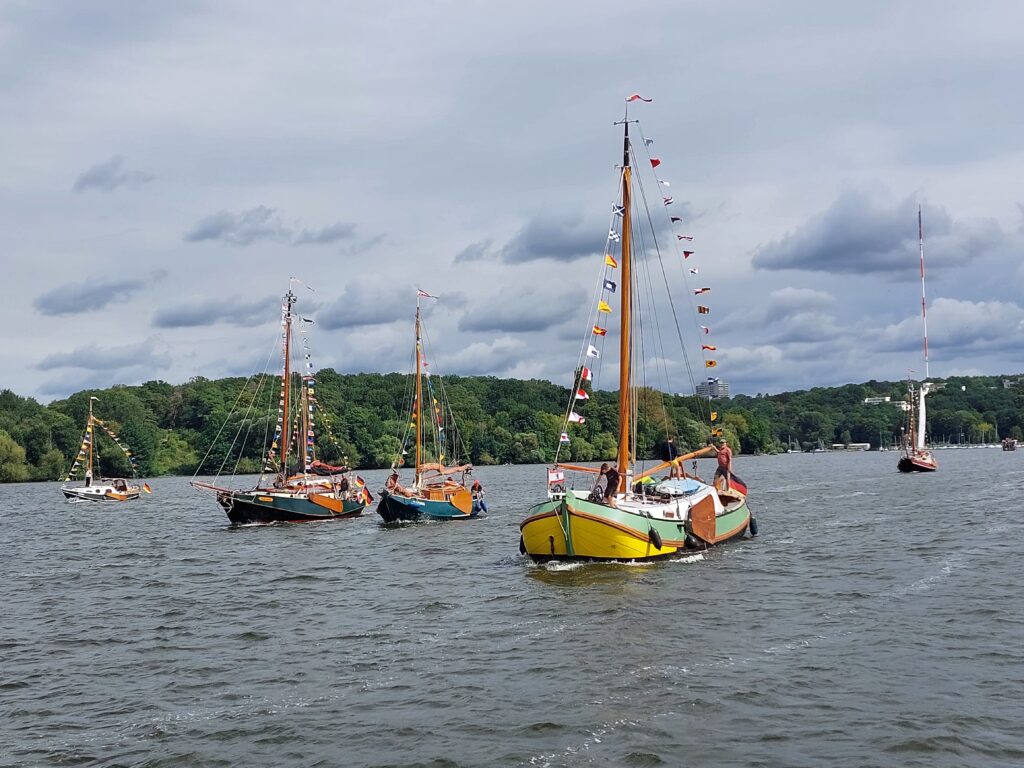 Vier geschmückte Schiffe sind auf dem Stößensee in Berlin unterwegs - es sind alte traditionelle Schiffe mit einem flachen Boden, die so genannten Plattbodenschiffe.