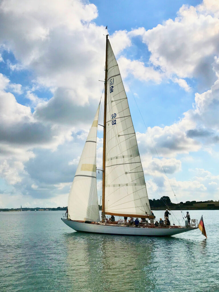 Eine große klassische Yacht segelt unter deutscher Flagge bei leichtem Wind in den schwedischen Schären