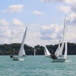 Jollen mit weißen Segeln auf einem grünblauen See