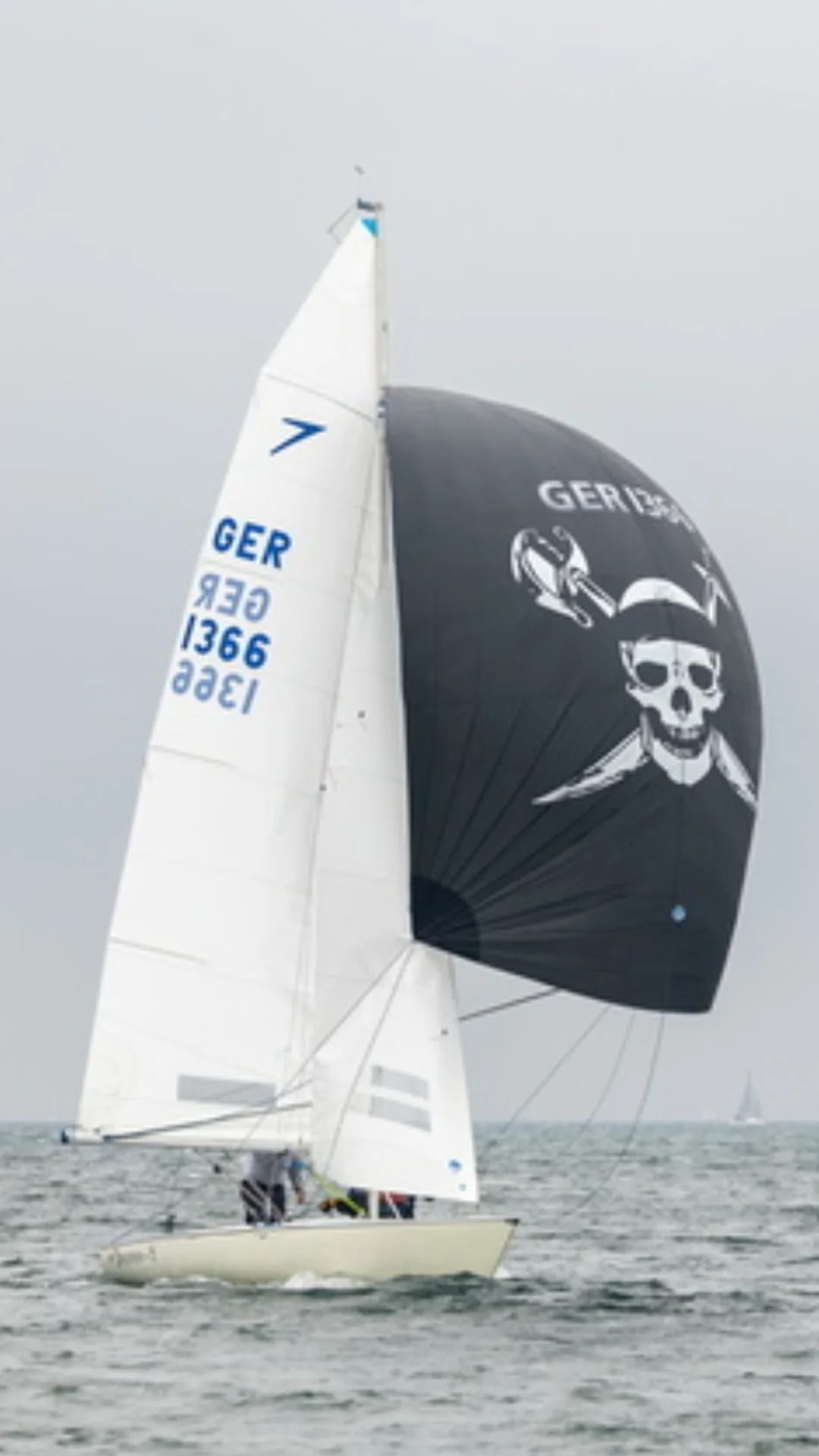 Ein Jolle mit einem schwarzen Spinnacker den ein Piratenkopf ziert.