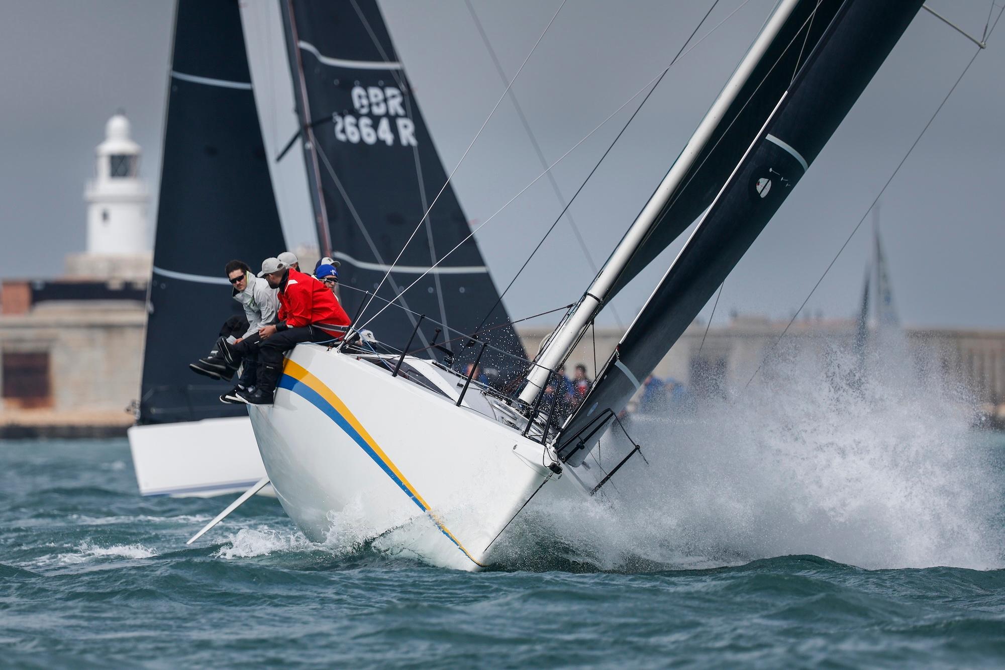Eine Yacht mit einem weißen Rumpf vor der Kulisse einer Stadt.