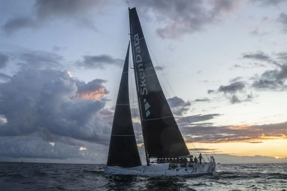 Eine große Yacht mit schwarzen Segeln vor dem Sonnenuntergang auf der Ostsee.