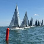 Mehrere Segelboote vom Typ J/24 fahren bei einer Regatta auf eine rote Stabtonne zu