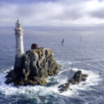 Ein Felsen mit Leuchtturm und Yachten