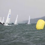 Jollen auf einer Regatta bei trübem Wetter, im Vordergrund eine große gelbe Regattatonne.