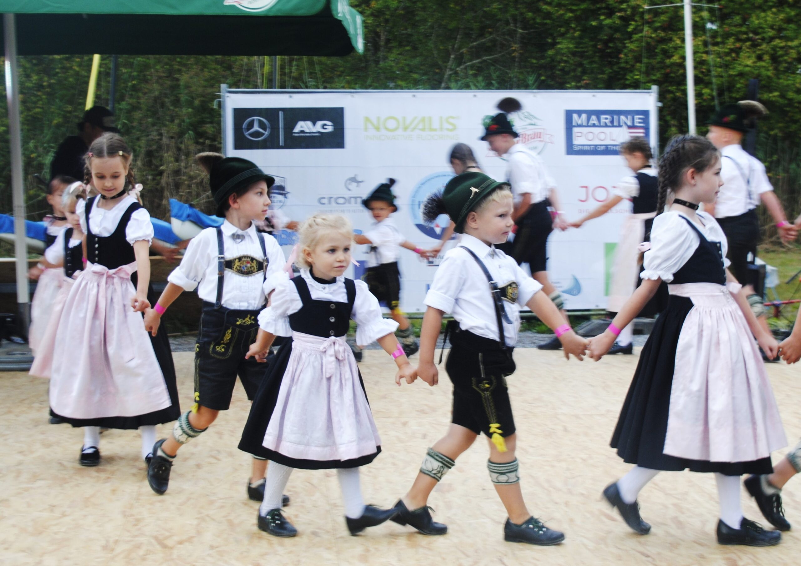 Kinder in Trachten halten sich an den Händen.