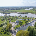 Das Foto von oben zeigt einen Hafen für Segel- und Motorboote an einem Fluss.