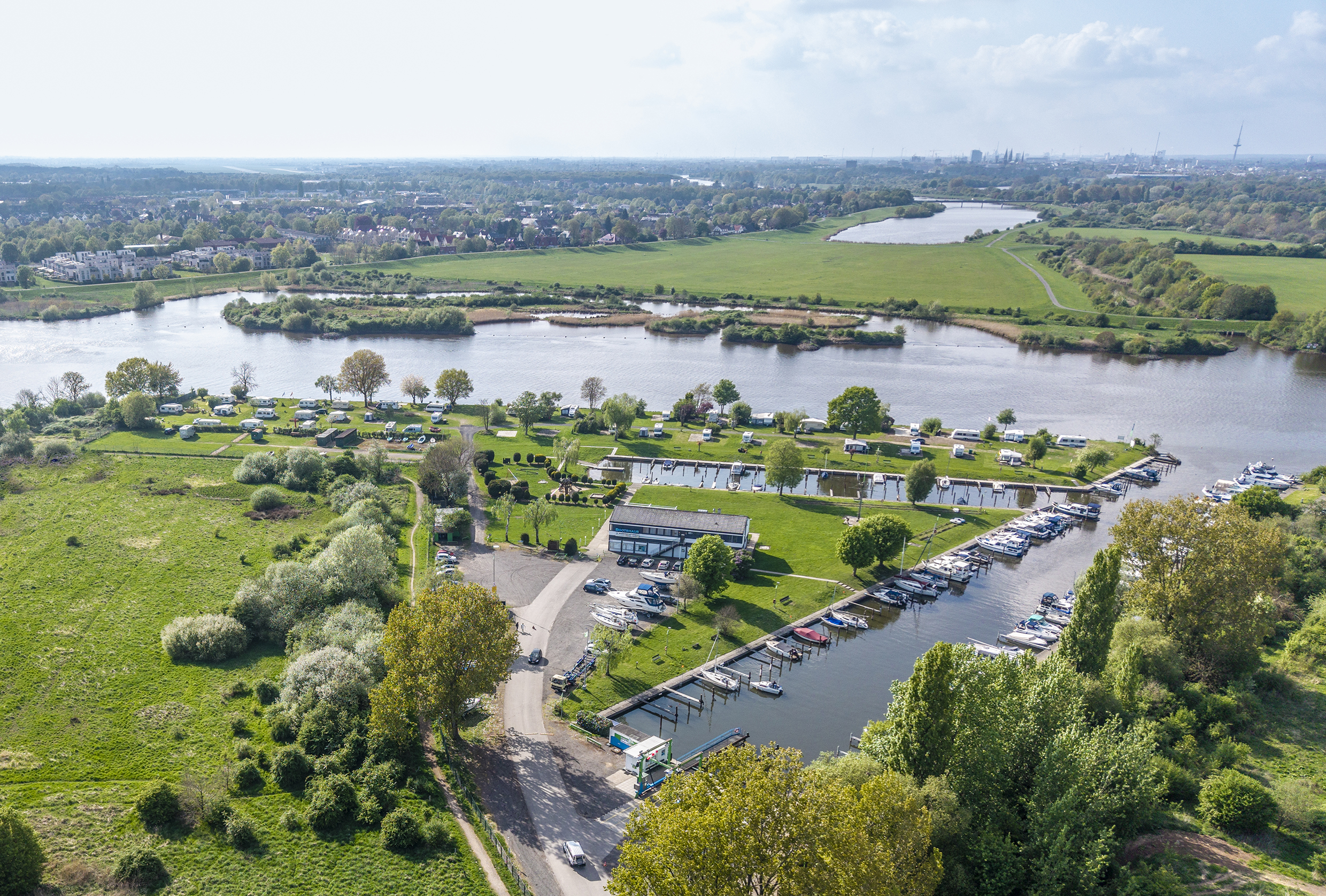 Das Foto von oben zeigt einen Hafen für Segel- und Motorboote an einem Fluss.