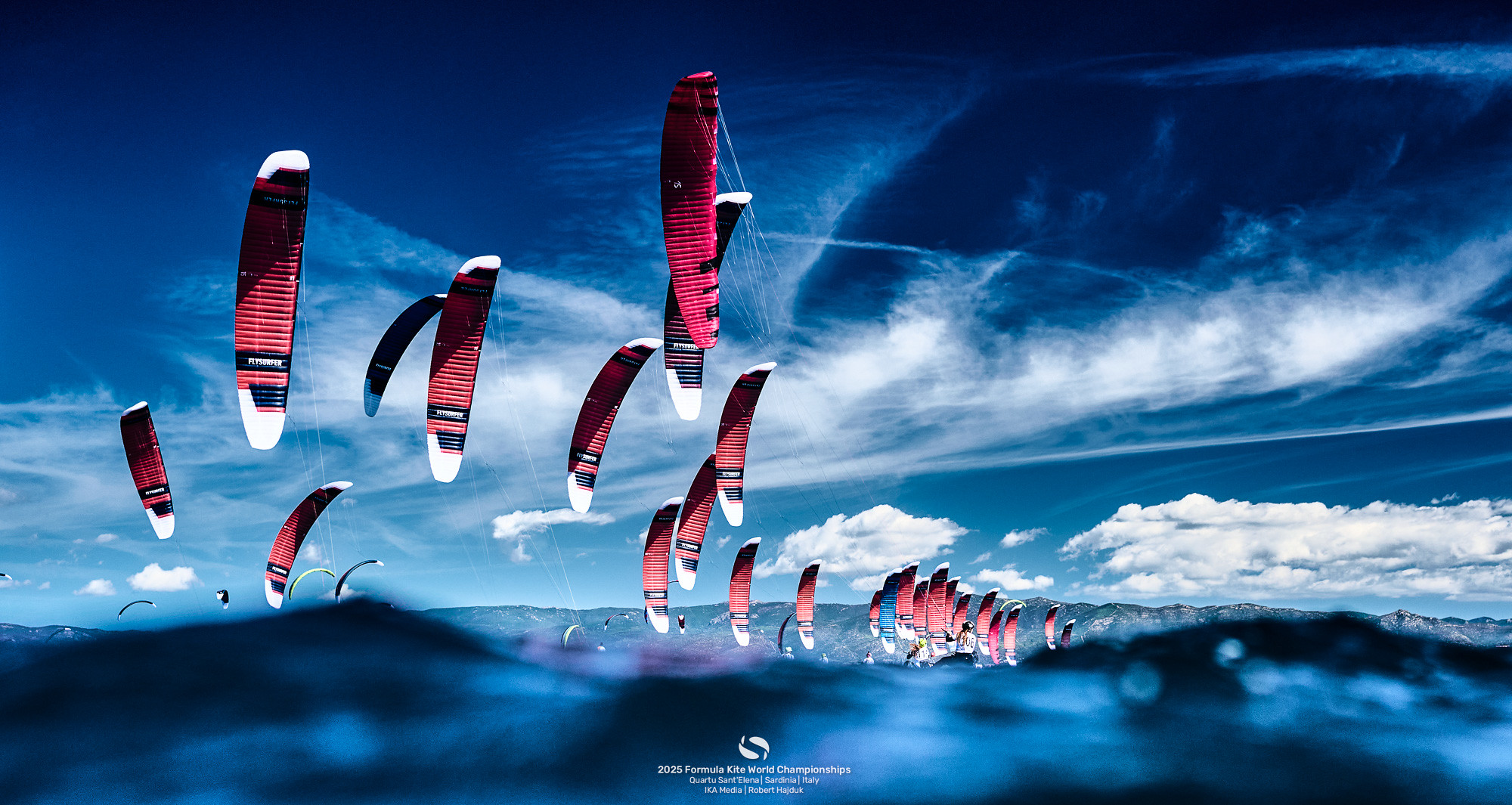 Viele Kites die wie große Drachen aussehen vor blauem Himmel.