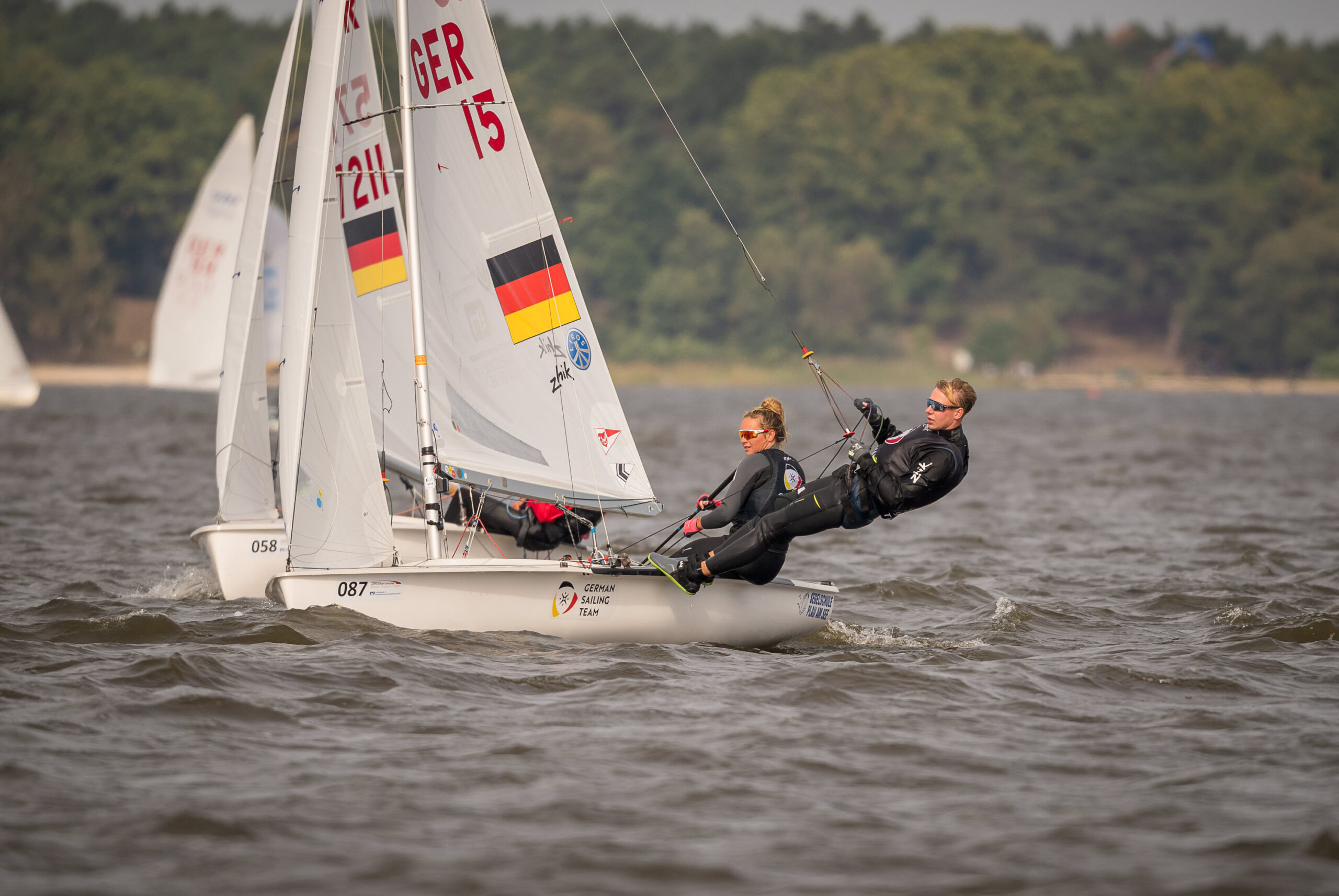 Zwei Segler auf einer 470er Jolle, im Segel ist die deutsche Flagge zu erkennen, dazu die Segelnummer 15. Auf dem weißen Rumpf steht German Sailing Team.