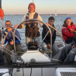 Sechs junge Seglerinnen und Segler im Cockpit einer Yacht.