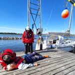 Eine Person liegt auf einem Steg und wird von einer anderen Person beatmet. Im Hintergrund ist ein Boot zu sehen. Es handelt sich um eine Übung in einem Kurs für Medizin auf See.