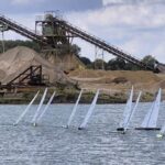 Ferngesteuerte Rennyachten auf einem See, im Hintergrund ist ein Förderband zu erkennen.