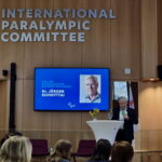 Jürgen Schwittai steht beim Internationalen Paralympischen Komitee auf einer Bühne. Hinter ihm ist auf dem Bildschirm zu lesen, dass er den Classification Award gewonnen hat.