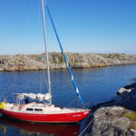 Ein rotes kleines Boot hat an einem Felsen festgemacht.
