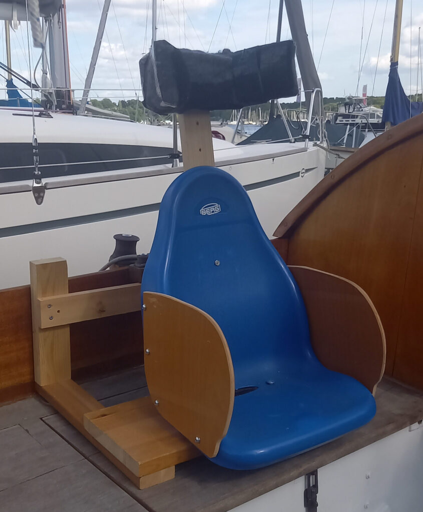Das Foto zeigt einen ausrangierten KettCar-Sitz, der an Deck eines Bootes festgeschraubt. Darauf kann ein Mensch mit schweren Behinderungen sicher sitzen und so mitsegeln.