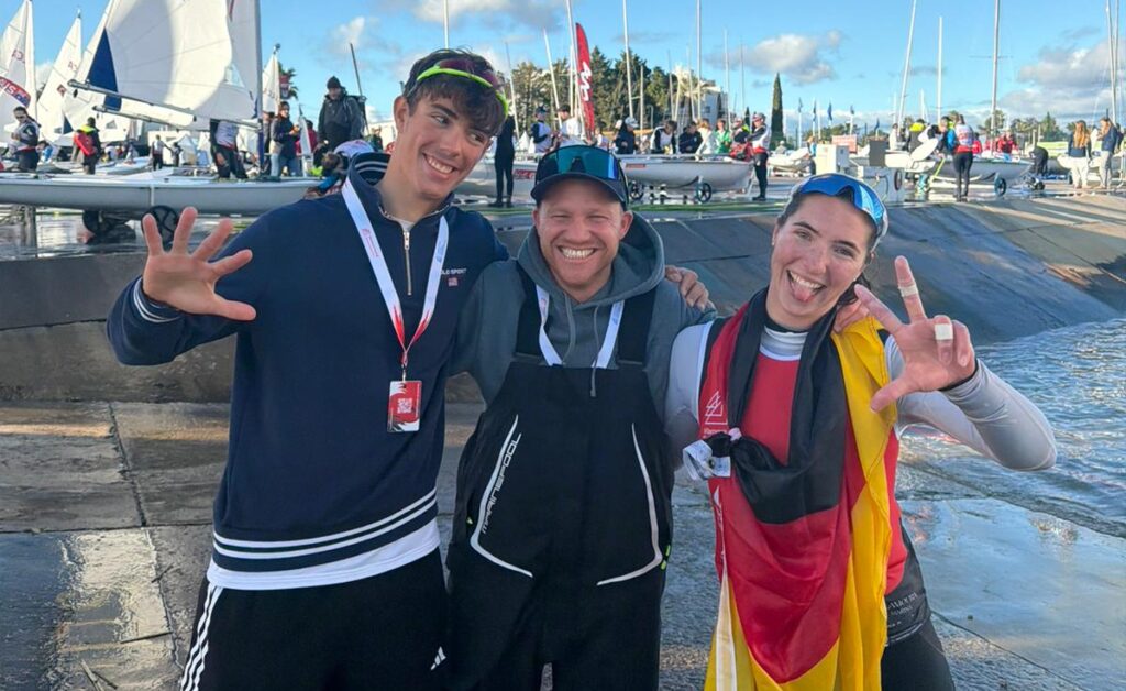 Levian Büscher, Trainer Fabian Kirchhoff und Mirja Dohle umarmen sich und lachen in die Kamera.