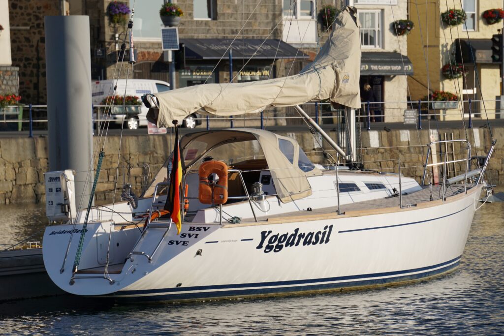 Eine Yacht mit deutscher Flagge liegt an einem Steg. Die Segel sind eingeschlagen.