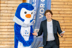 Der Jugendobmann Jonathan Koch hält ein Grußwort, während neben ihm das Maskottchen der Seglerjugend „Skippi“ steht.
