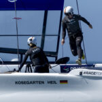 Zwei in schwarz gekleidete Segler auf dem foilenden F50 Katamaran des SailGP