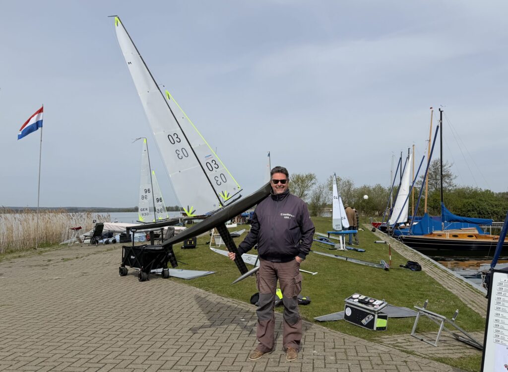 Ein Segler zeigt seine Modell-Segelyacht Marblehead an Land. Sie ist größer als der segler selbst