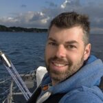 Sebastian Wache an Bord seines Schiffes, er lacht fröhlich in die Kamera