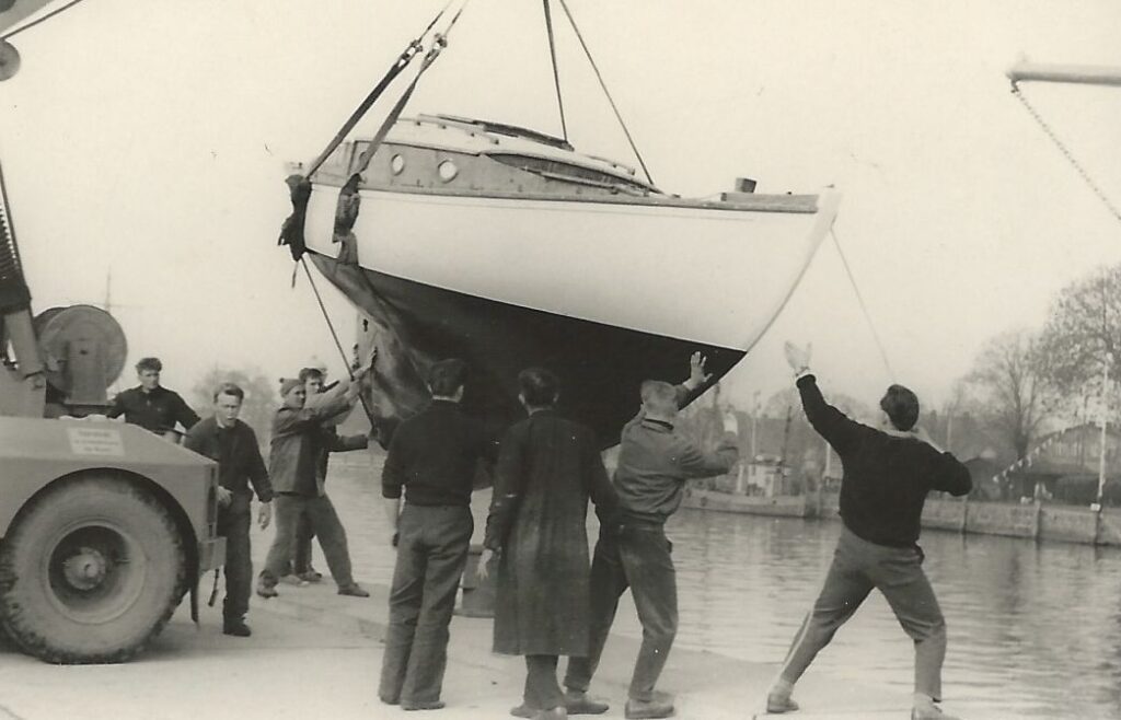 Eine Yacht hängt am Kran. Einige Männer dirigieren das Boot. Es soll ins Wasser gelassen werden.
