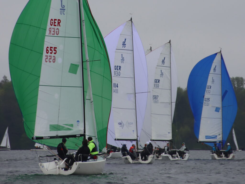 Segelboote mit weißen und grünen Segeln segeln bei einer Wettfahrt.