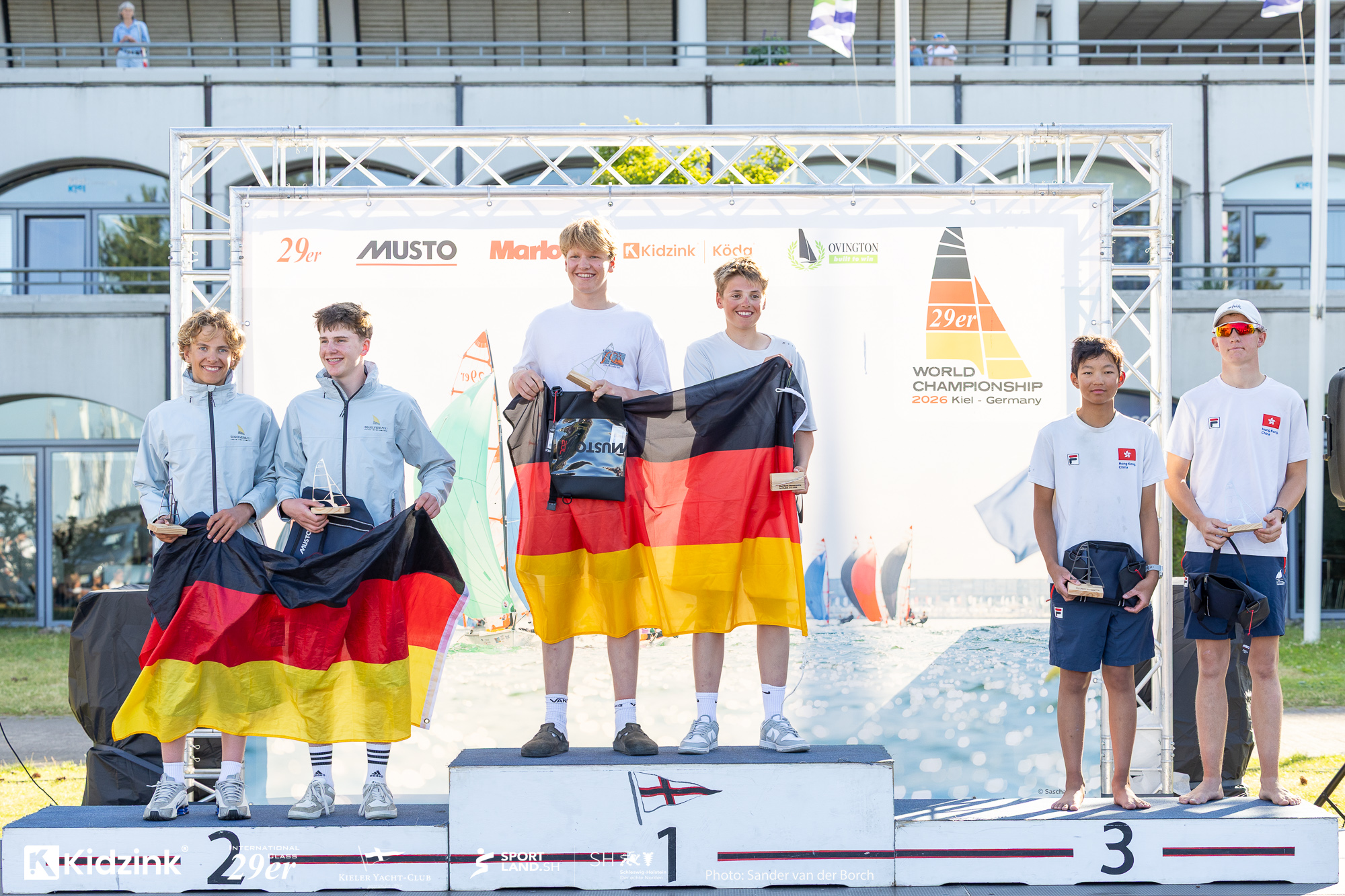 Drei Jugendliche stehen auf dem Podest bei der Siegerehrung nach einer Regatta.