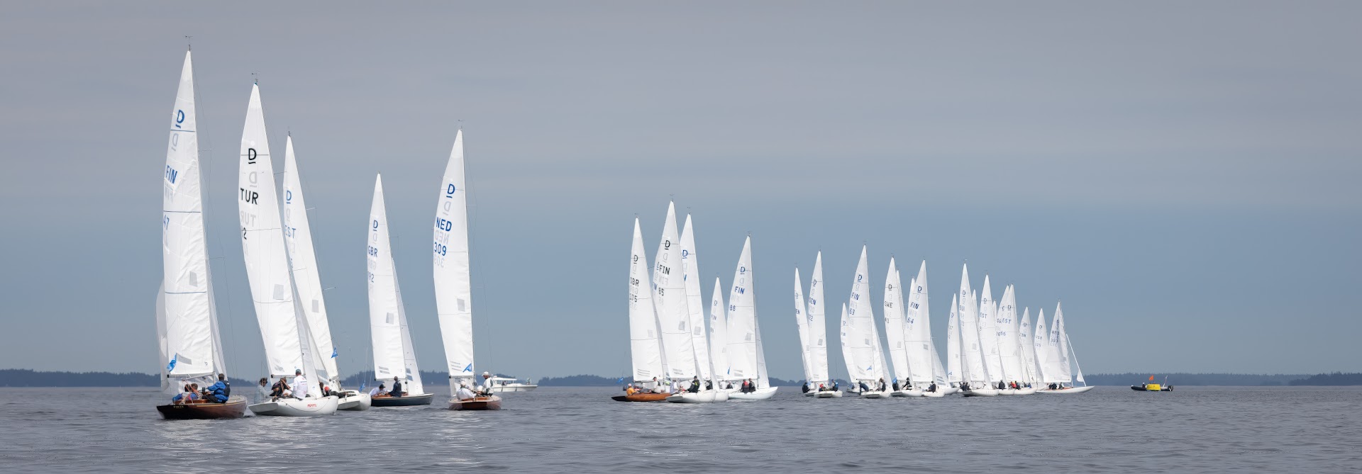 Viele Boote vom Typ Drachen bei wenig Wind in den finnischen Schären.