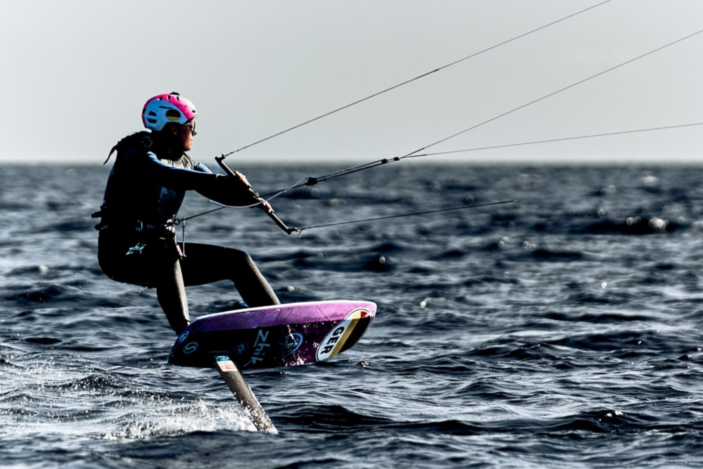 Eine Frau foilt mit dem Kite. Sie trägt einen Helm.