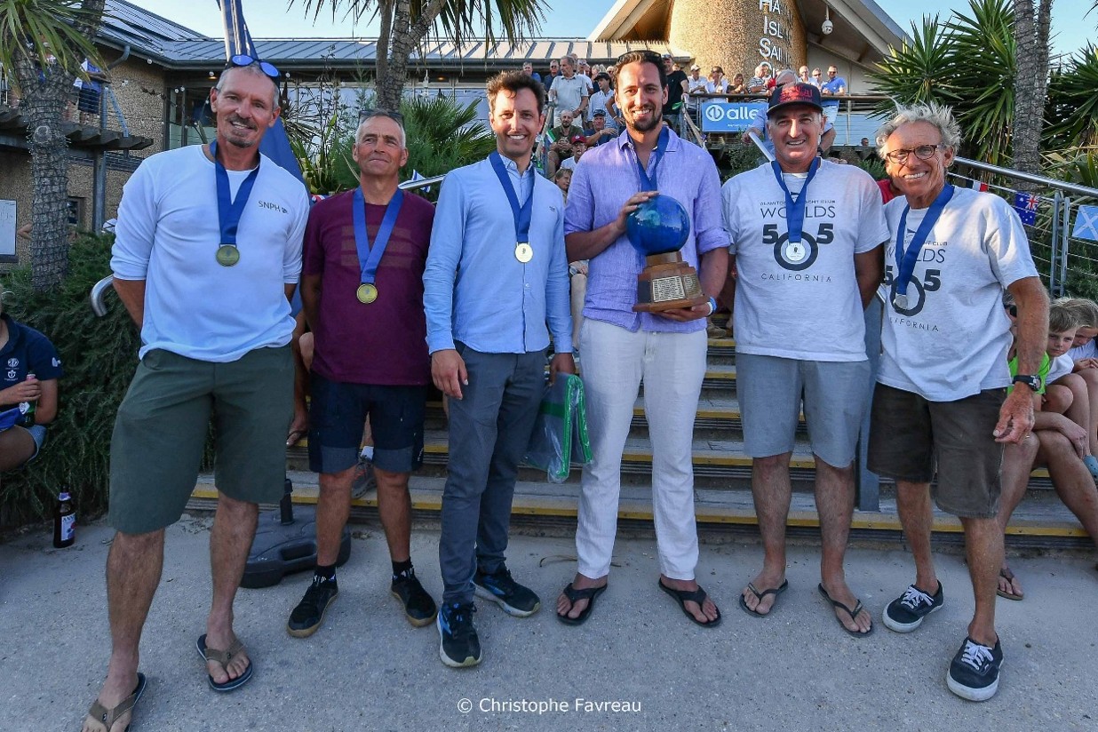 Sechs Männer bei einer Siegerehrung für Segler, in der Mitte die Weltmeister im 505er 2026