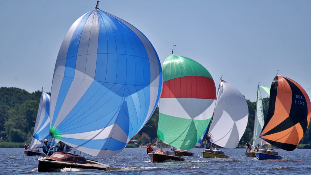 Hölzerne Boote vom Typ 15er Jollenkreuzer segeln unter Spinnaker auf dem Zwischenahner Meer