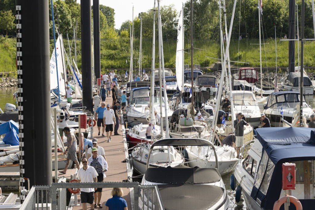 Viele Segelboote und Motorboote liegen eng beieinander im Hafen. Die Sonne scheint.