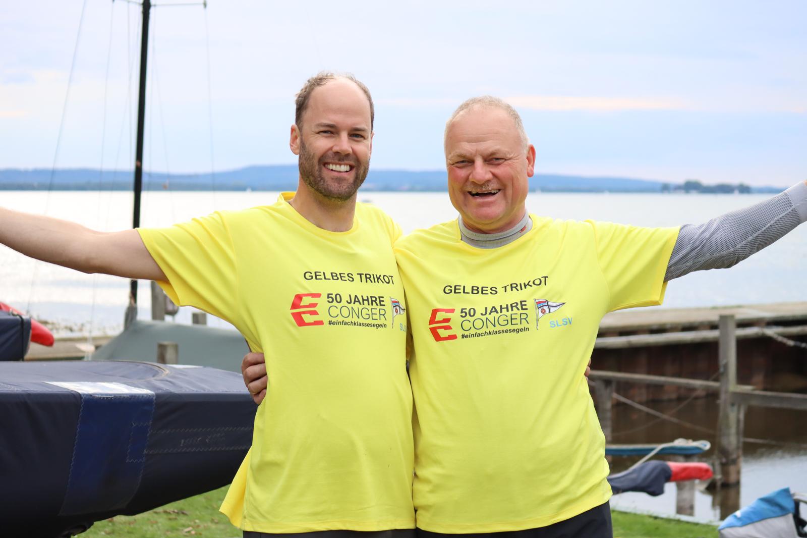 Amr in Arm zwei Männer in gelben T-Shirts, es sind Juiuls Raithel und Wolfang Goeken, die gerade die Deutsche Meisterschaft der Conger 2026 gewonnen haben.