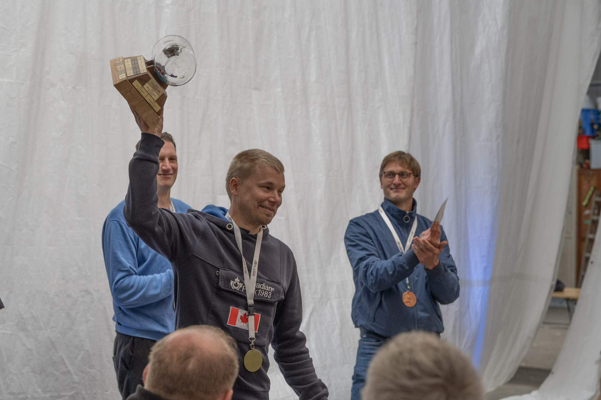 Ein Mann mit einer Medaille um den Hals hält den Wanderpreis der Contenderklasse in die Höhe