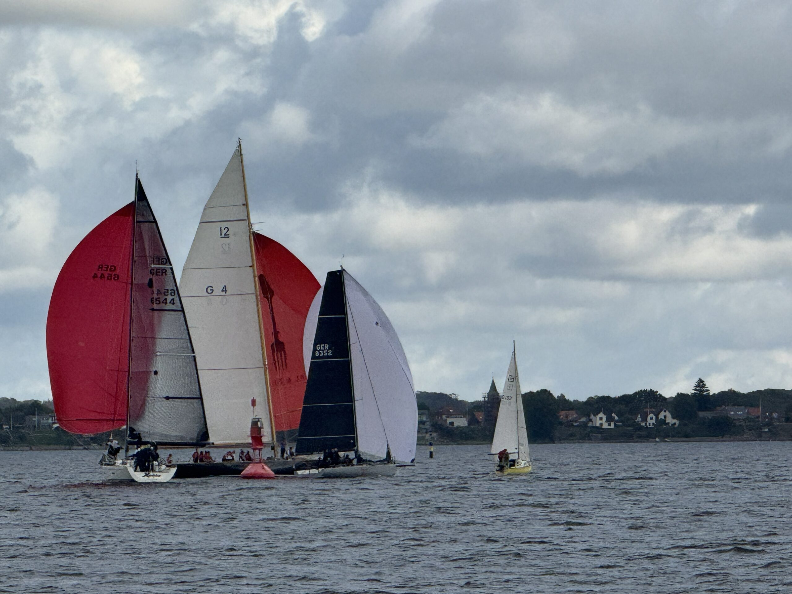 Große und kleine Yachten runden bei trübem Wetter eine Regattatonne