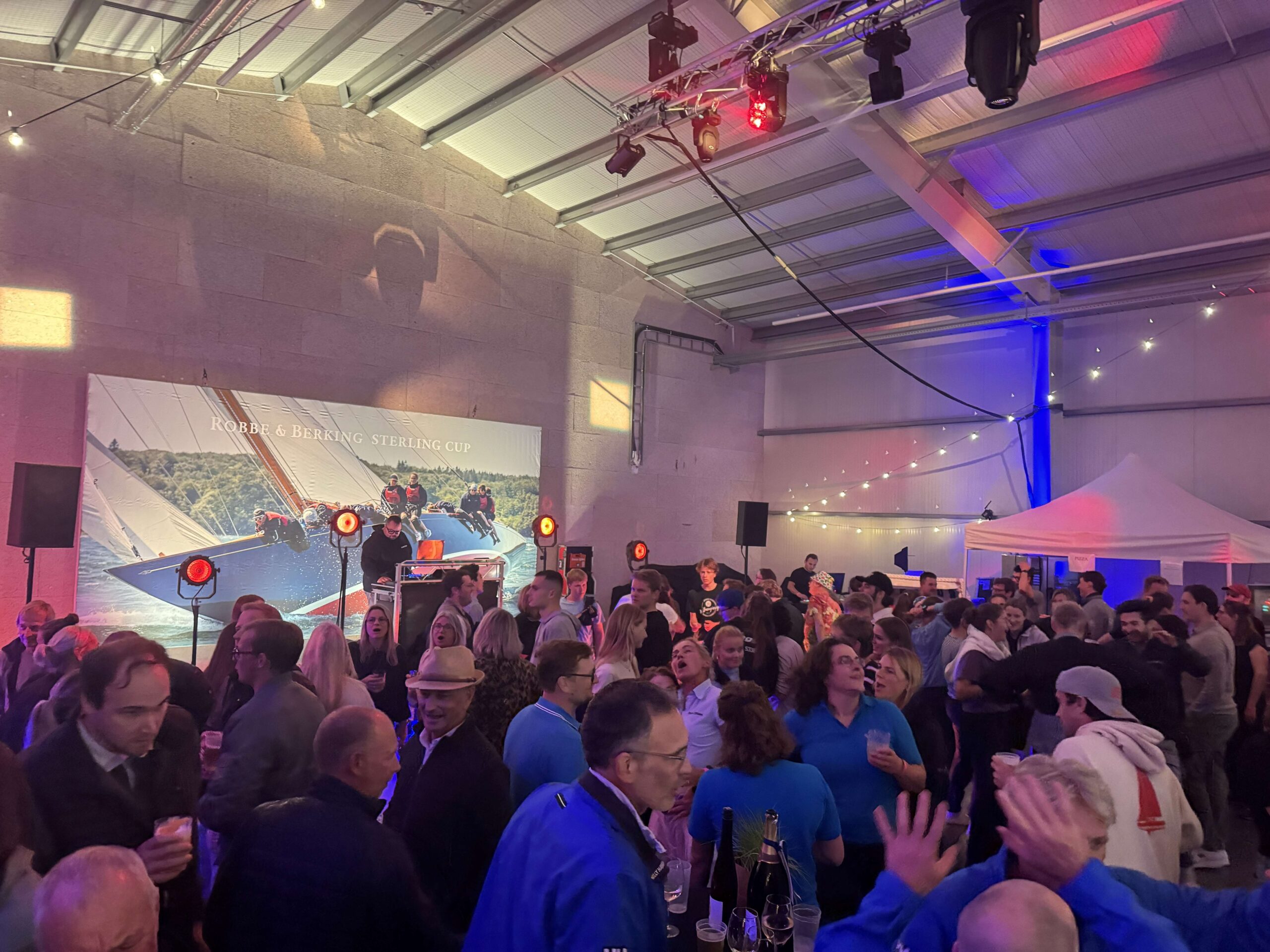 Eine Party von vielen Seglerinnen und Segler in einer Bootshalle