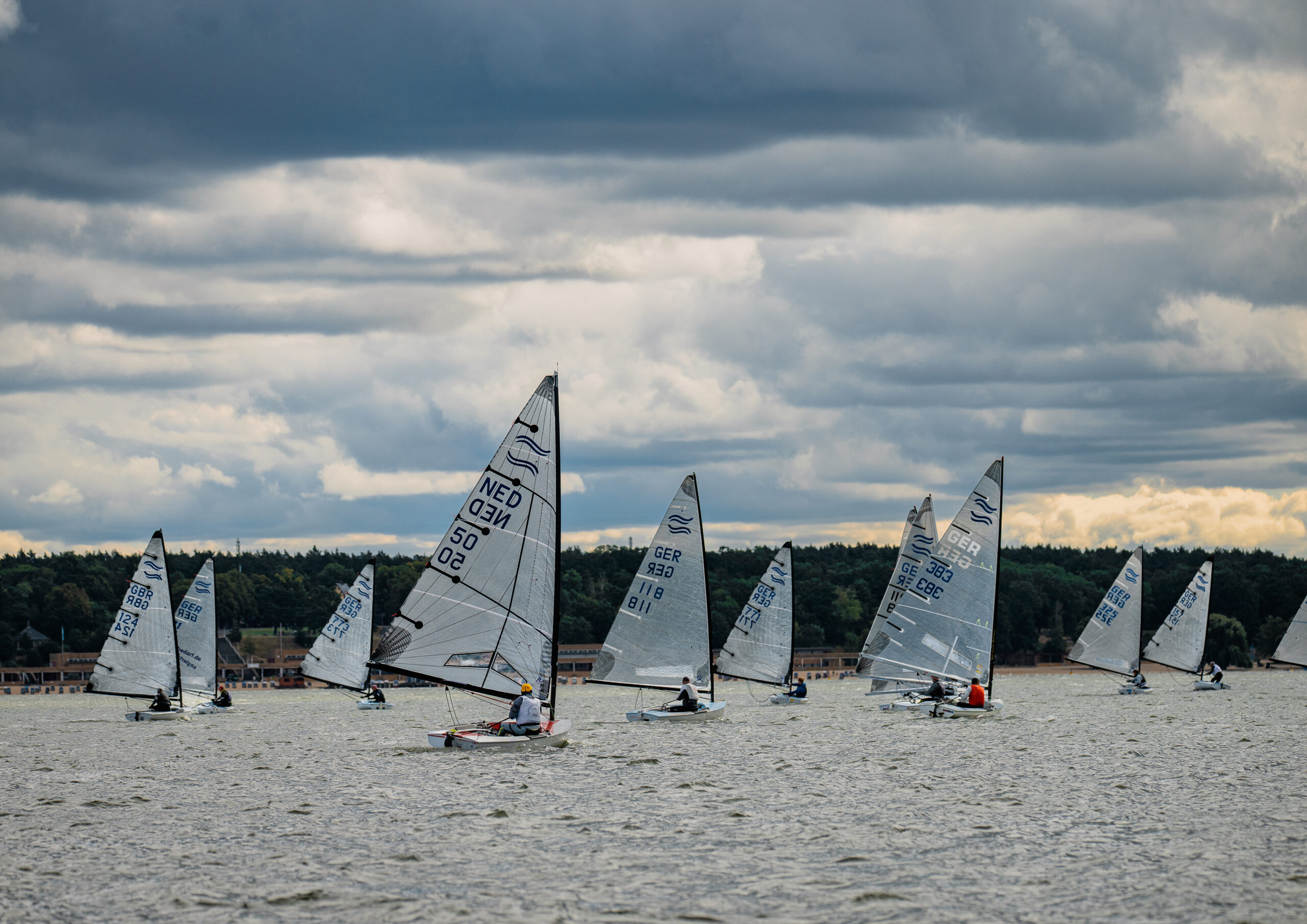 Mehrere Jollen vom Typ Finn Dinghy von hinten auf dem Berliner Wannsee.