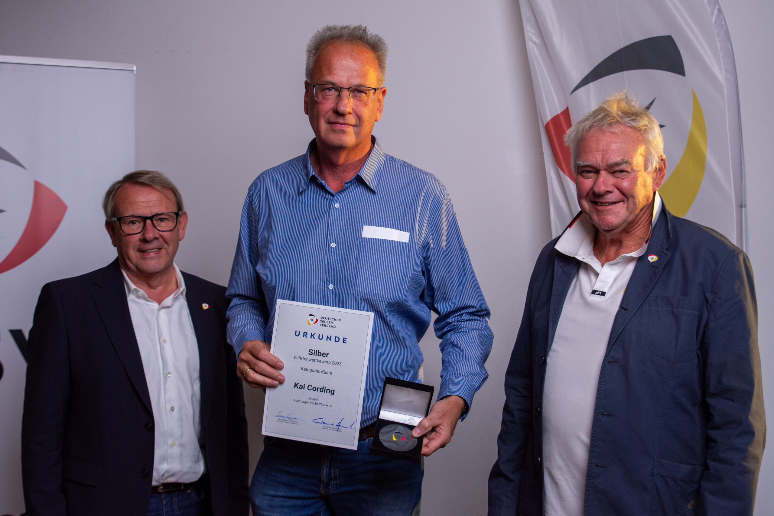 Ein Mann mit einer Urkunde für einen Segelpreis in der Hand.
