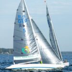 Eine 2.4mR Yacht mit weißem Rumpf und einem blauen Streifen, dazu ein Foliensegel mit der Nummer 5