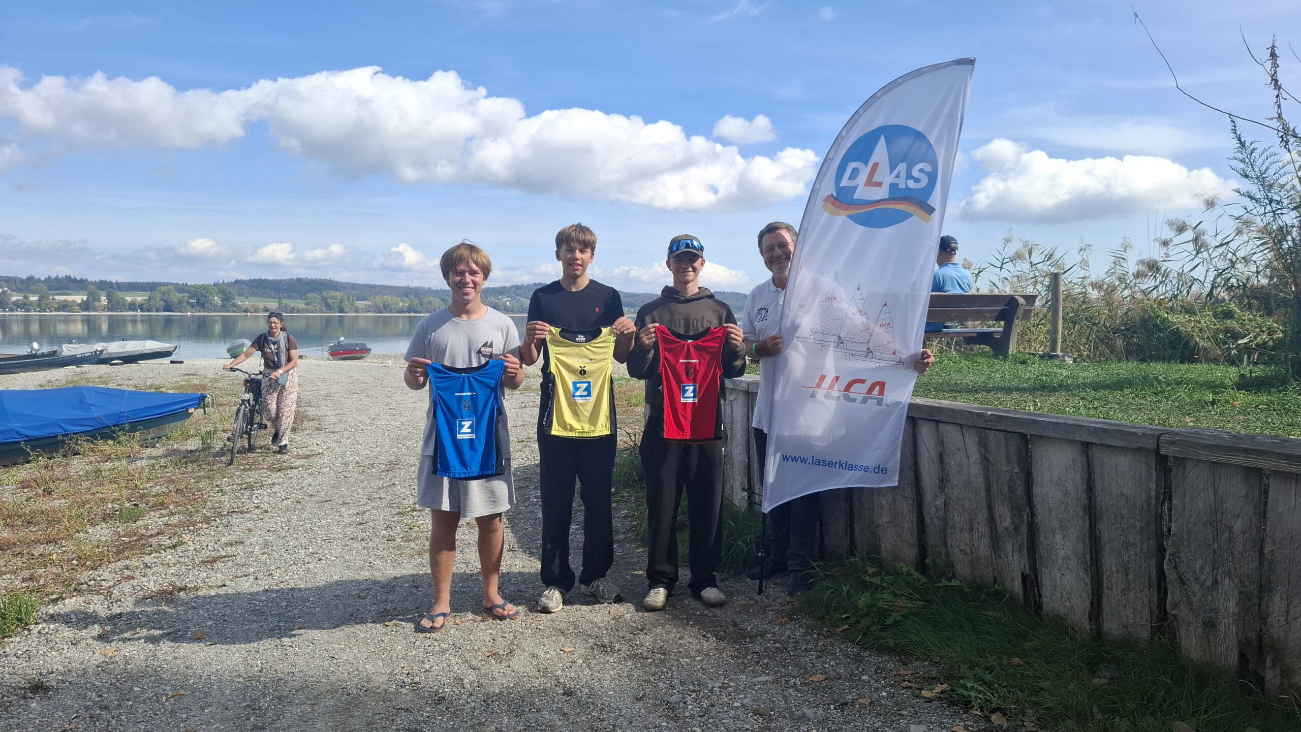 Drei erfolgreiche junge Segler mit einem gelben, einem blauen und einem roten Trikot.